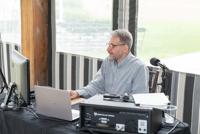Early wedding DJ setup with laptop and sound equipment, focused on managing music and audio during a small reception